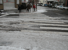 横断歩道を雪が堆雪しており、横断歩道の線が所々隠れている写真