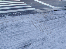 歩道の点字ブロックが、雪で覆われ真っ白になっている写真
