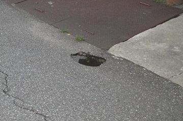 道路に小さな空洞の穴が開いている写真
