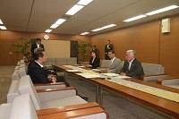 長い机に3名の関係者の人が座り締結式を行っている写真