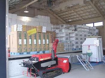 倉庫内に段ボールがたくさん積まれていて、その前に赤い機械が置かれている大和町防災備蓄倉庫内を写真