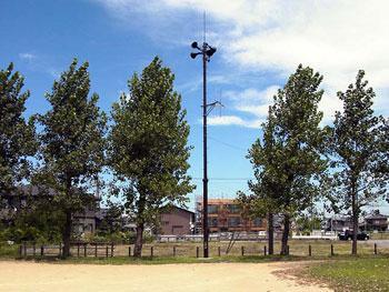 広場の5本の木の間に建てられた防災無線システムの写真