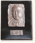 高峰賞という文字とひげが生えた高峰譲吉博士の顔が彫られている盾の写真