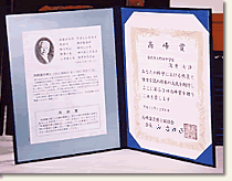 右側に高峰賞と書かれ、左に高峰譲吉博士の顔写真が入っている書類が貼られた賞状ホルダーの写真