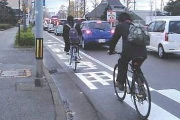自転車専用レーンを使い2台の自転車が通学している後ろ姿を写した写真