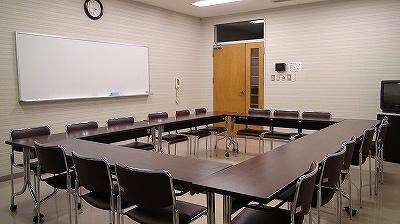 中央を四角く囲むように、長い机と椅子が並べられ、左奥にホワイトボードが見える第3研修室の写真