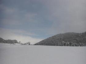 雲が多くうっすら見える青空と辺り一面が雪で覆われている写真