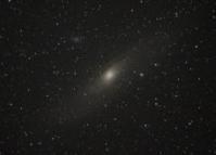 夜空に映る中心にやや黄色が掛かる大きな星とその中心を囲むような小さな星から連なるアンドロメダ大星雲（M31）を撮影した写真