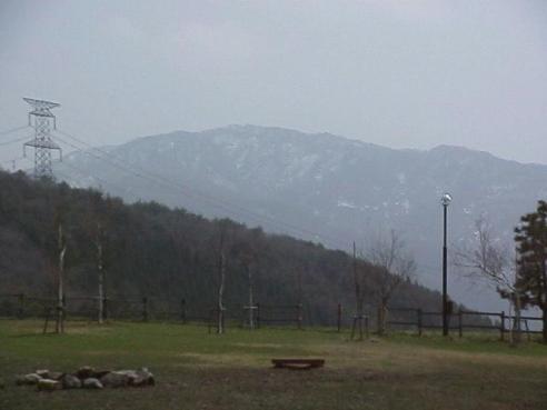 平成15年4月13日に撮影された少しかすんで見える山頂部分に残雪が残っている様子の奥医王山の写真