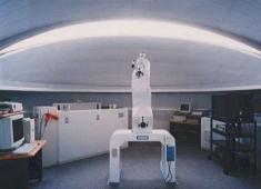 天体観察室の屋内を撮影した写真。天井は丸く、中央には望遠鏡と思われる物体が置かれている。