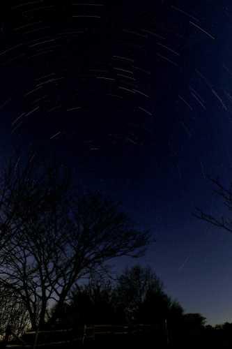 真っ暗な夜空にうっすらと北極星を中心に回る流れる星たちの写真