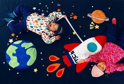 宇宙飛行士アートに寝そべる子供達の写真