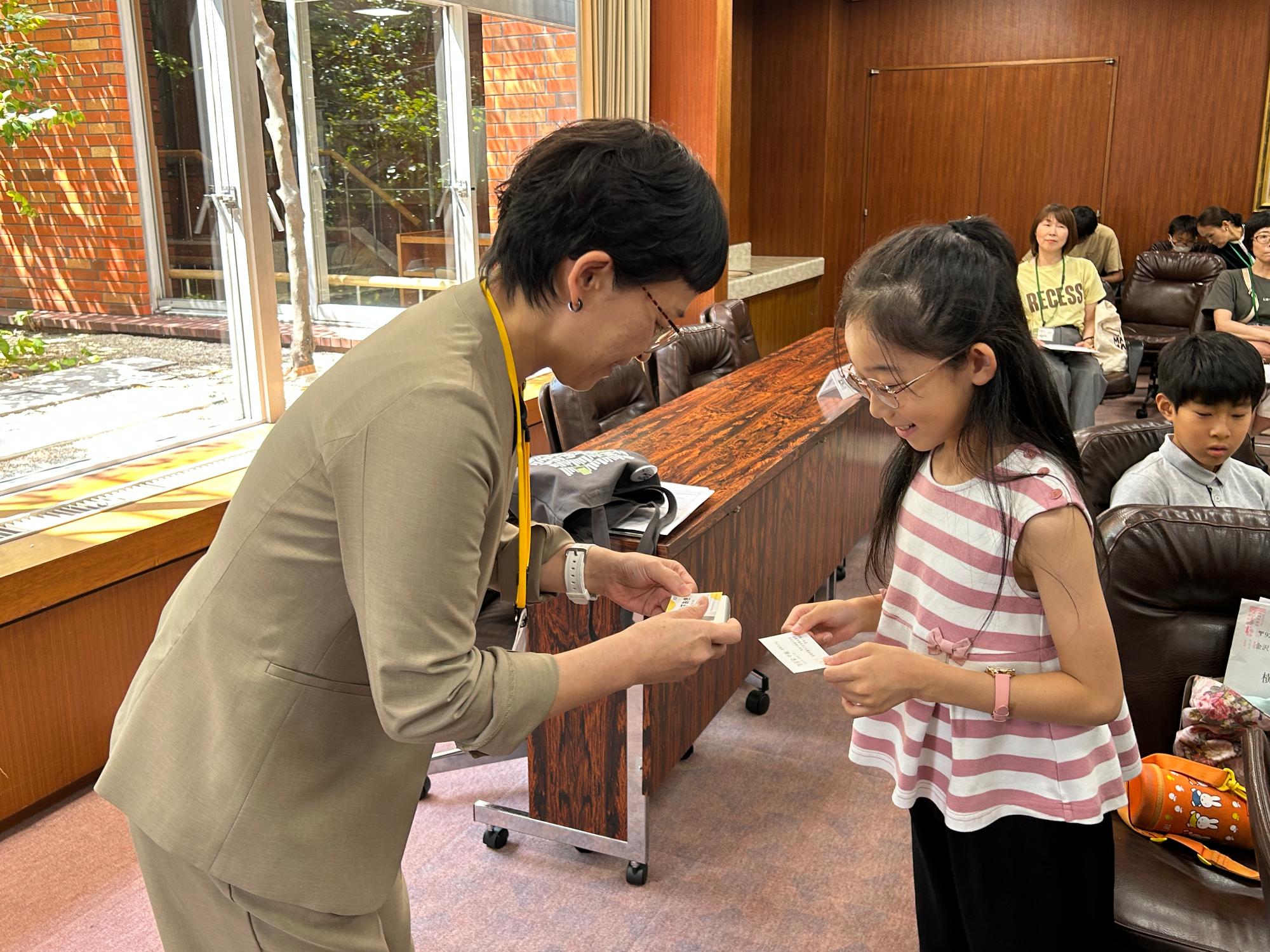 議会室内で議員と子ども議員が名刺交換をする写真